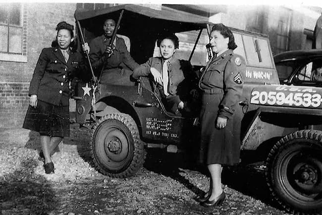 The four women are in uniform but are at ease.