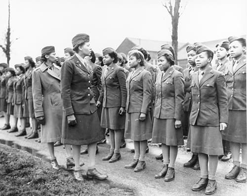 This is a black-and-white photograph of the 6888 standing at attention while Lt. Col. Adams reviewed the troops.