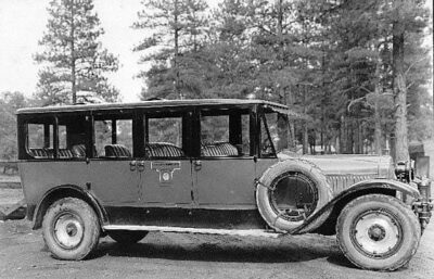 This is a photo of a Fred Harvey touring car. It looks well used and may have chains on the tires. There are four rows of seats, and the photo collection identifies it as a "transportation bus.