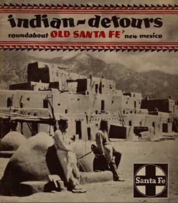 This is a color copy of a Fred Harvey brochure describing Indian Detours. The photo shows two people standing in front of a multi-story Indian adobe home. The Santa Fe logo is in the right bottom corner.