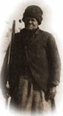 Very dark photo of Mary Fields. She is derssed in a jacket and cap and holds her rifle in her right arm.