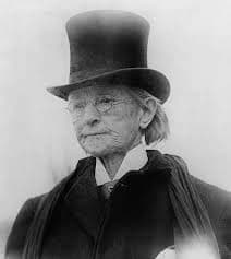 In this photograph, Walker is dressed in her good suit and wears the stovepipe hat. She wears glasses, and her hair is cropped short.