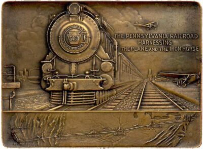 It appers to be a brass paperweight with a large image of a railroad image on the left. Two planes on teh right, and a map of the cross-country route underneath.