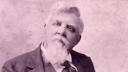 A sepia toned photo of Judge Isaac Parker. He is dressed in a suit and has a big bushy white beard.