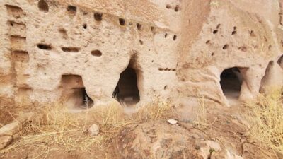 This is a color photograph of one type of cliff dwelling made by Native Americans. This is literally little doorways and windows carved out of the cliffs.