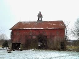 Red barn with cupola for ventilation. Snow on ground.
