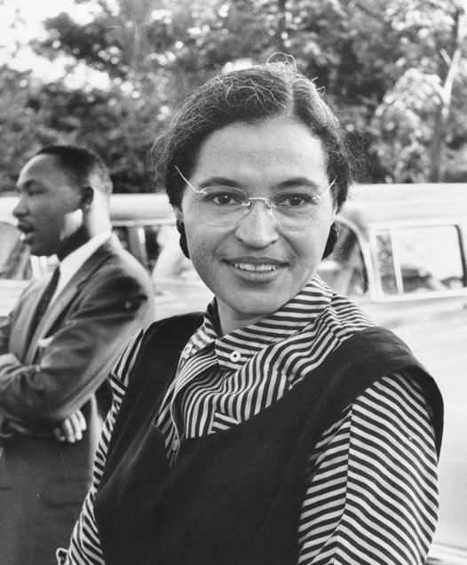 a black-and-white photograth of Rosa Parks with Martin Luther King standing behind her in conversation with someone. public domain