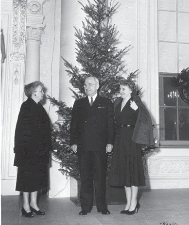 A black-and-white photo of Bess and Harry Truman in front of an outdoor Christmas tree at the White House. Visitor unidentified. National Park Service