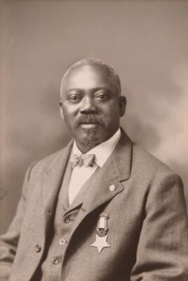 This professional photograph shows an older Carney dressed in a gray suit and wearing the Medal of Honor. Perhaps the photo was take in 1900 when he received the Medal.