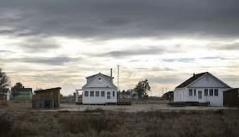 Two white wooden structures stand out in this photograph of Allensworth. The sky looks threatening but the town looks well.