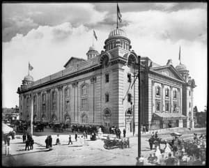This is a black-and white photo of the newly built Denver auditorium with turrets in each corner of the building. Each turret is topped off with a flag.