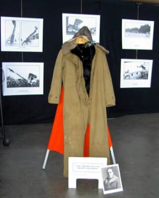 Pilot flying gear, prepared for cold weather with heavy coat and ear muff hat.