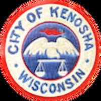 The patch shows a bird (a pelican?) holding scales of justice. The City of Kenosha is in blue. A red circle surrounds the exterior circle.