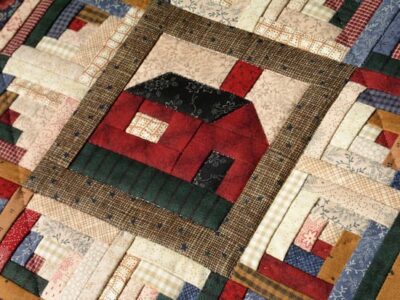 Though the quilt would have featured many log cabins, this photograph depictson of the squares showing a cabin with door, window, and chimney.