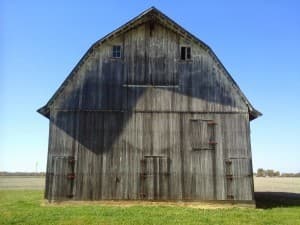 Grey weathered barn with a bright blue sky behind it.