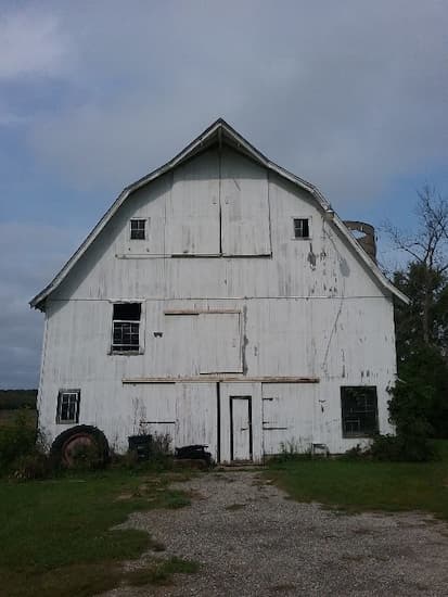 White barn that looks in use. There is an upper door where hay would have been loaded into the hayloft.