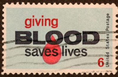 This is a stamp from 1969 showing that the U.S. continues to encourage blood donations. The pale blue background has a blood dropas part of the background.
