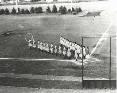 This is a newspaper photo of two teams lining up in a V-formation before a game. The Star Spangled Banner would have been played at that time.